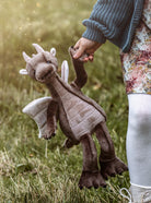 Person holding a plush dragon toy outdoors
