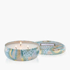 Candle in a decorative tin with a patterned lid on a white background