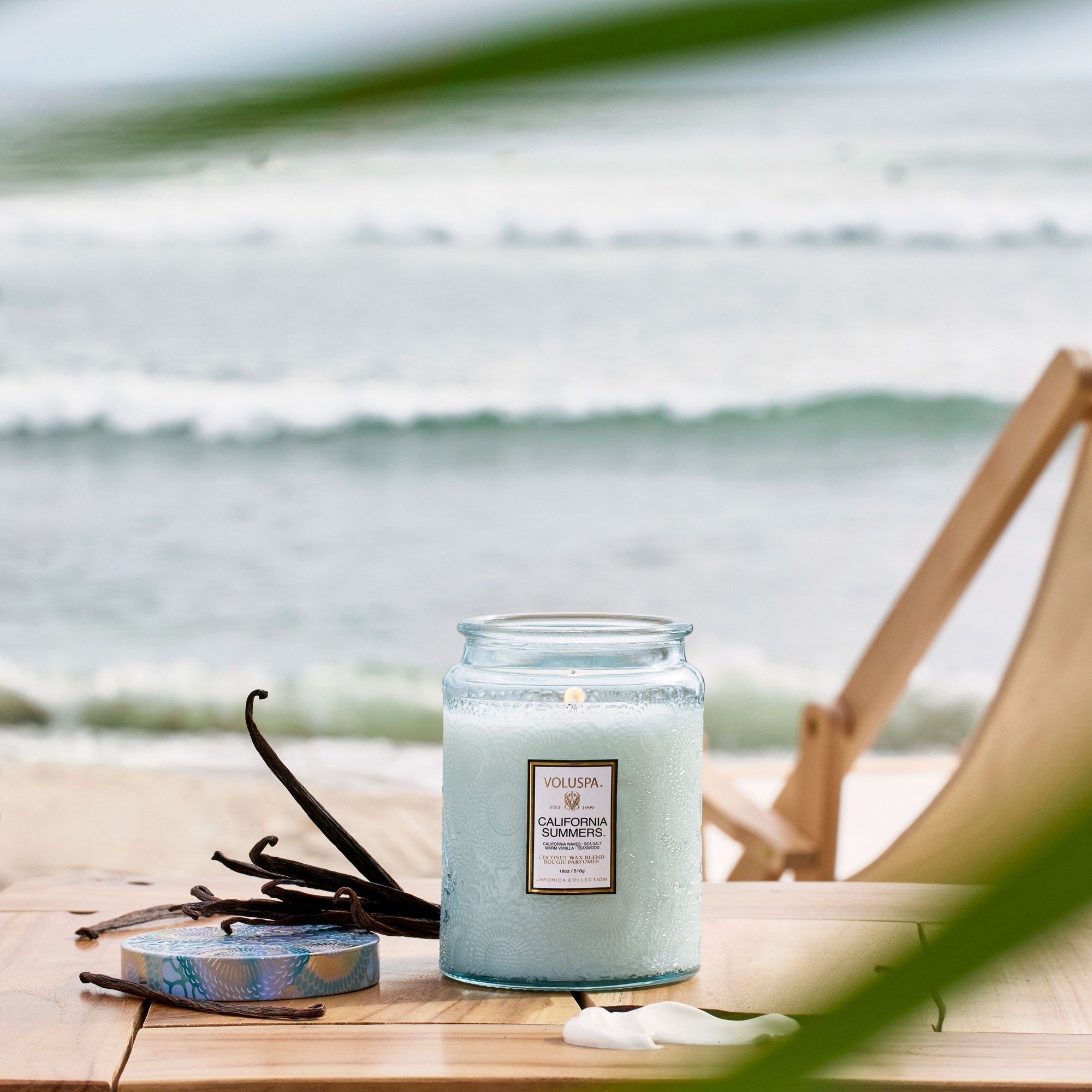 Candle with vanilla beans on a wooden table by the ocean