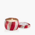 Red striped candle with a lit wick on a white background