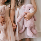 Blush plush kitty toy by Snuggle Bunnies, held by child, soft textured fur, white muzzle, black eyes, lifestyle shot