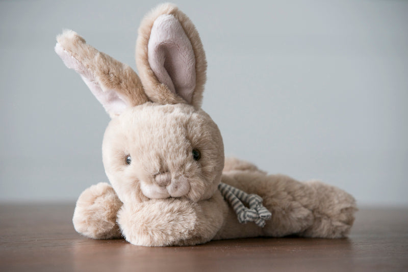 Plush rabbit toy with a striped scarf on a wooden surface