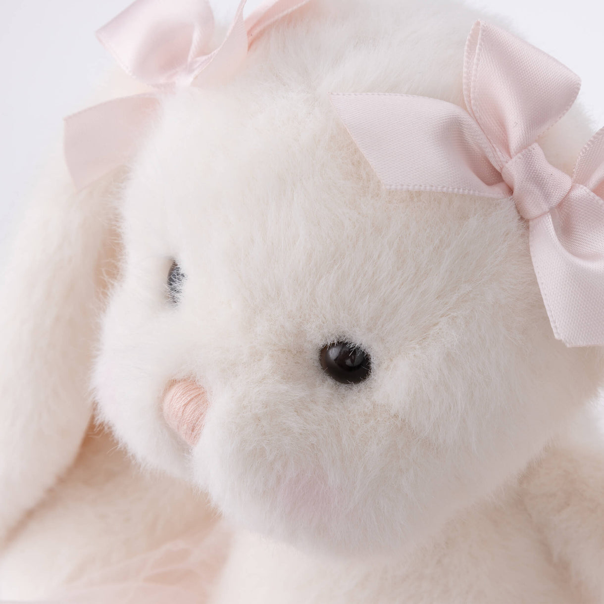Close-up of a plush toy with a pink bow on a light background