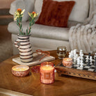 Candlelit living room with candles, a vase, and a chessboard on a coffee table.