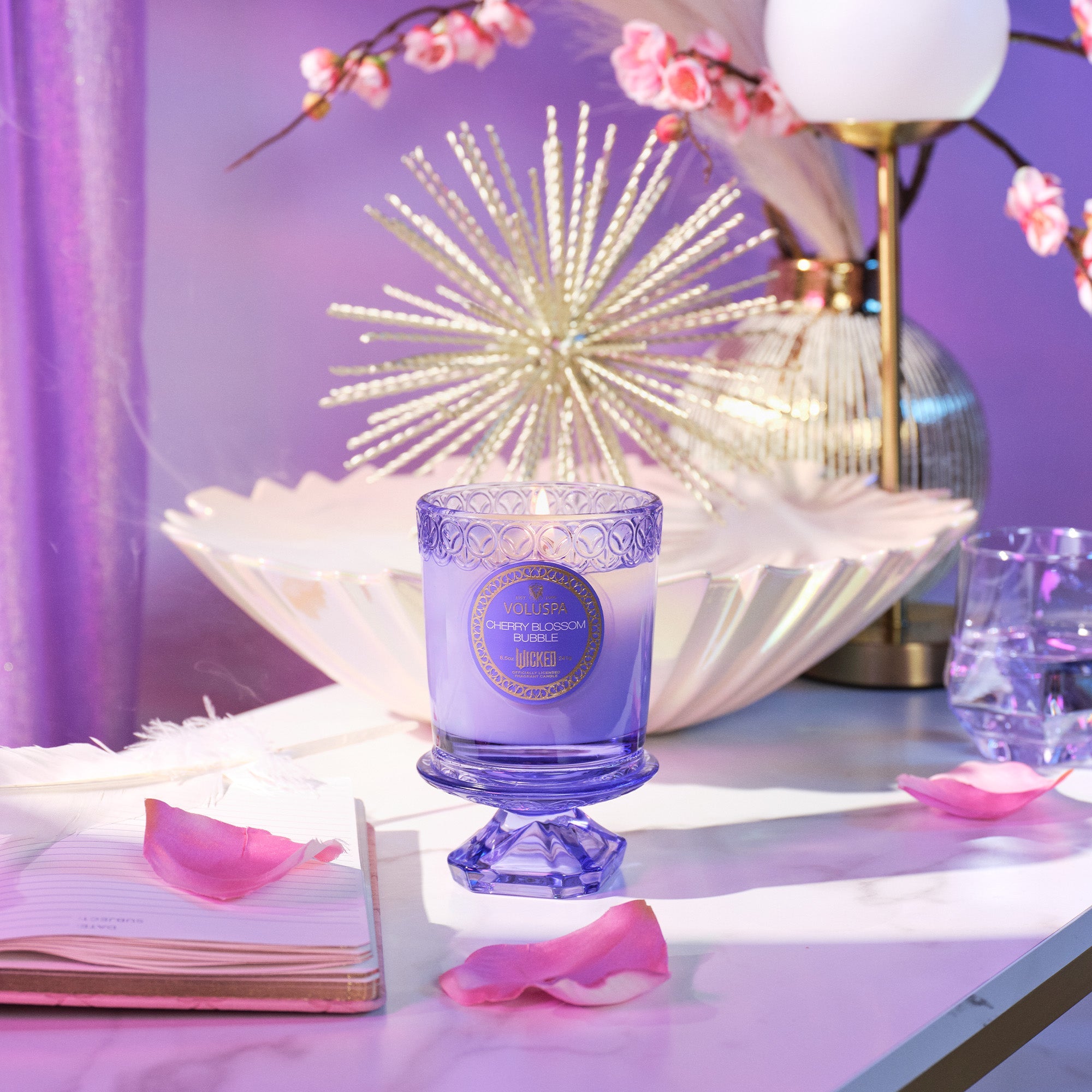 Decorative purple candle on a table with floral elements and soft lighting
