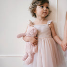Soft pink plush bear toy set, 12" and 8" sizes, held by child in light pink dress, side view, lifestyle shot