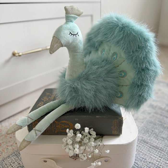 Plush peacock toy on a white stand with a neutral background