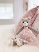 Gray plush cat toy wearing a pink dress with white polka dots.