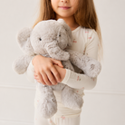 Soft gray plush elephant toy by Snuggle Bunnies, 12 inches, held by child in cream cherry-patterned pajamas, front view