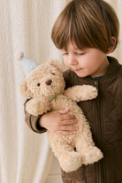 Child holding a teddy bear with a neutral background