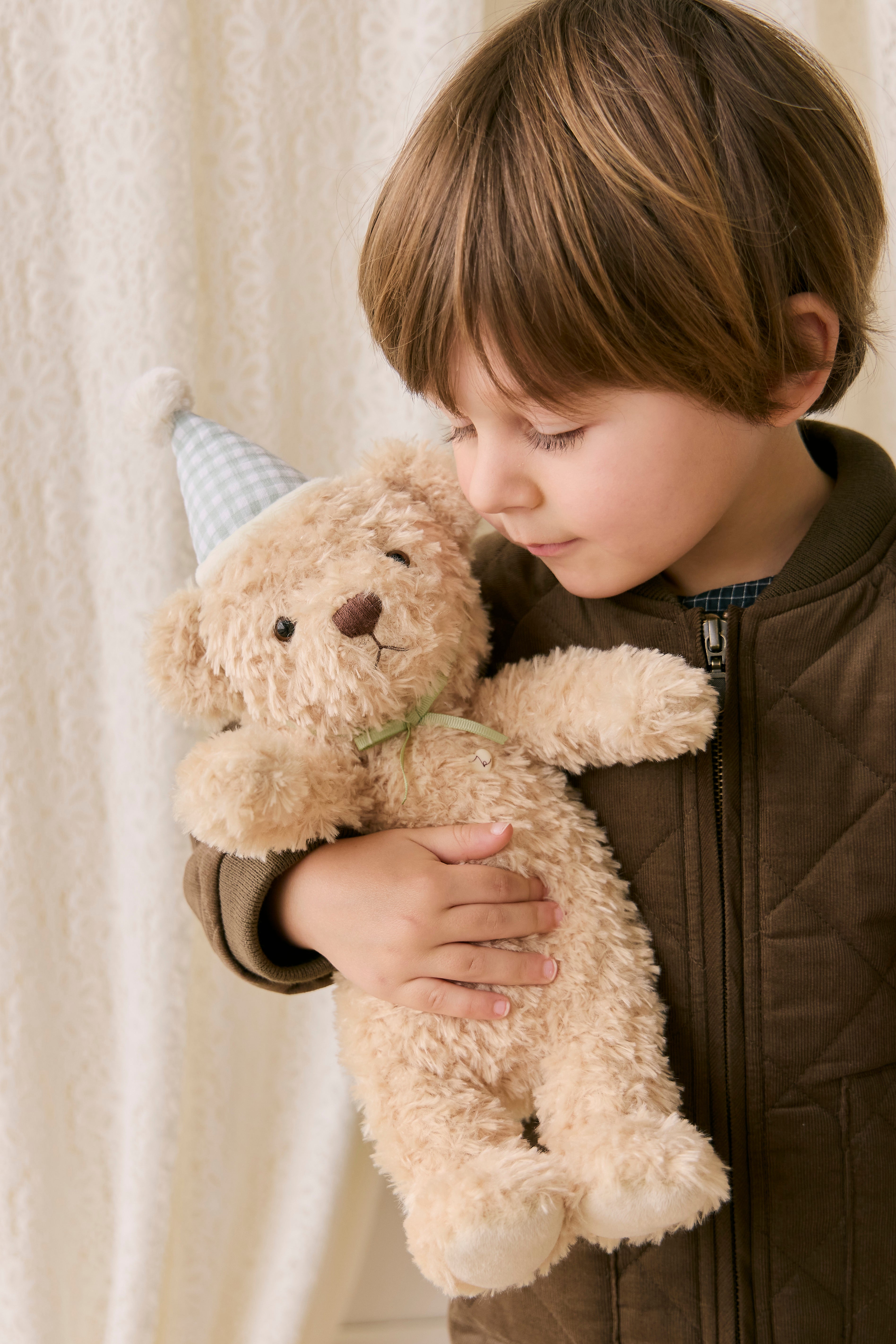 Child holding a teddy bear with a neutral background
