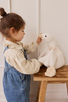 Child playing with a plush duck toy on a wooden table.