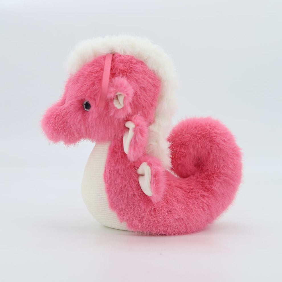 Pink and white plush dragon toy on a light gray background