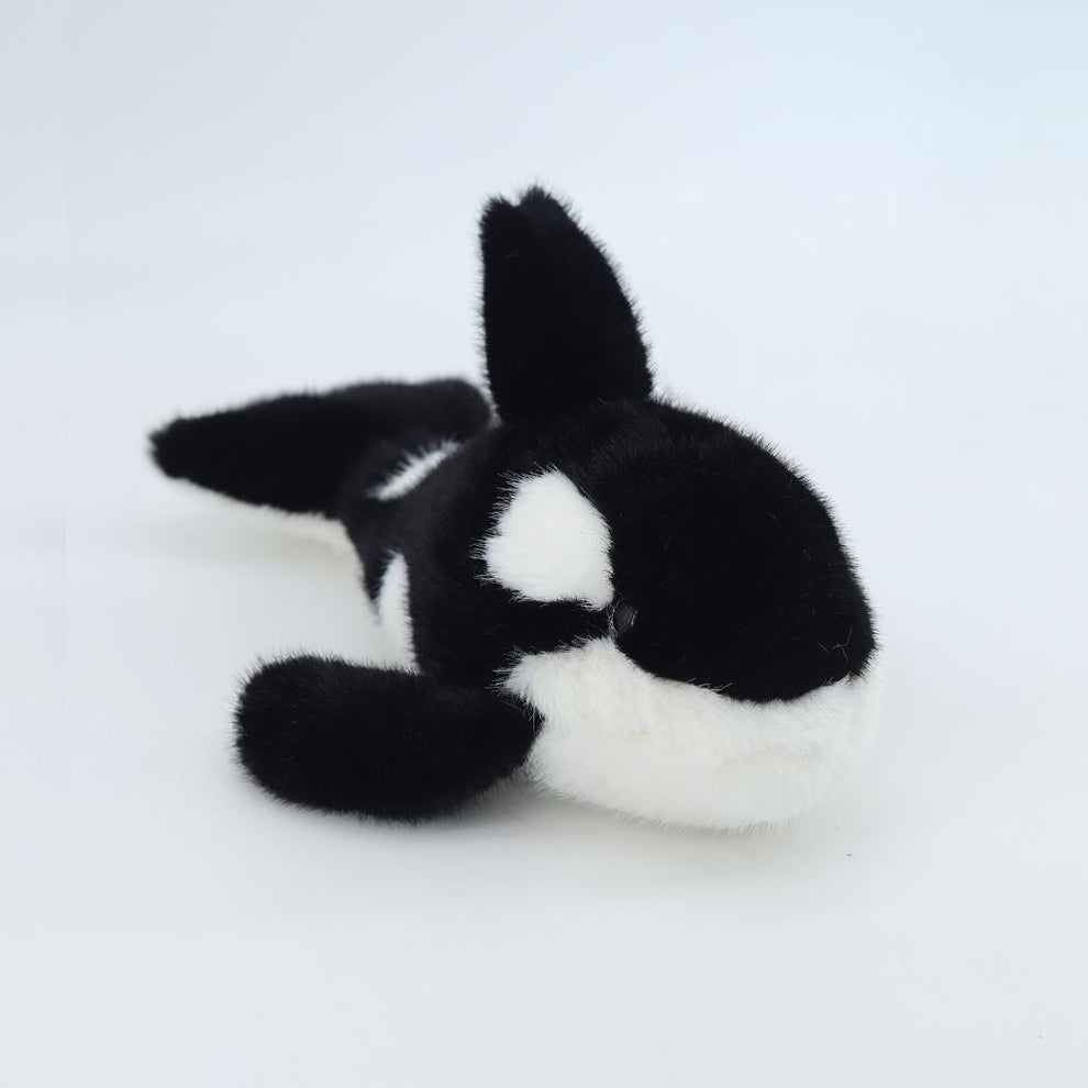 Black and white plush toy whale on a light gray background