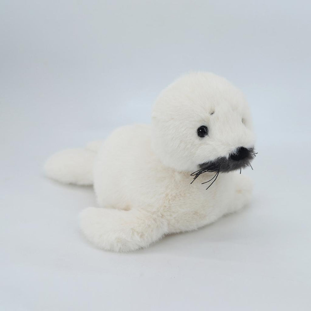 White plush toy seal with black accents on a light gray background