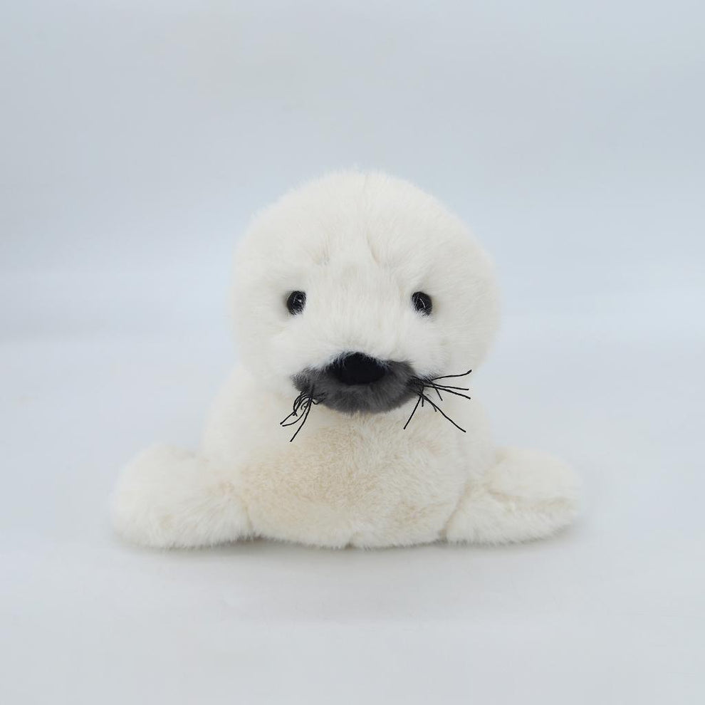 White plush toy seal with black accents on a light gray background
