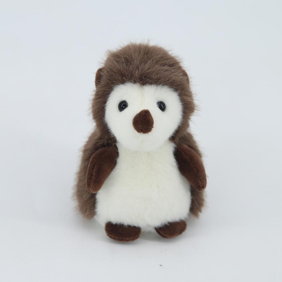 Stuffed toy penguin with brown and white fur on a light gray background