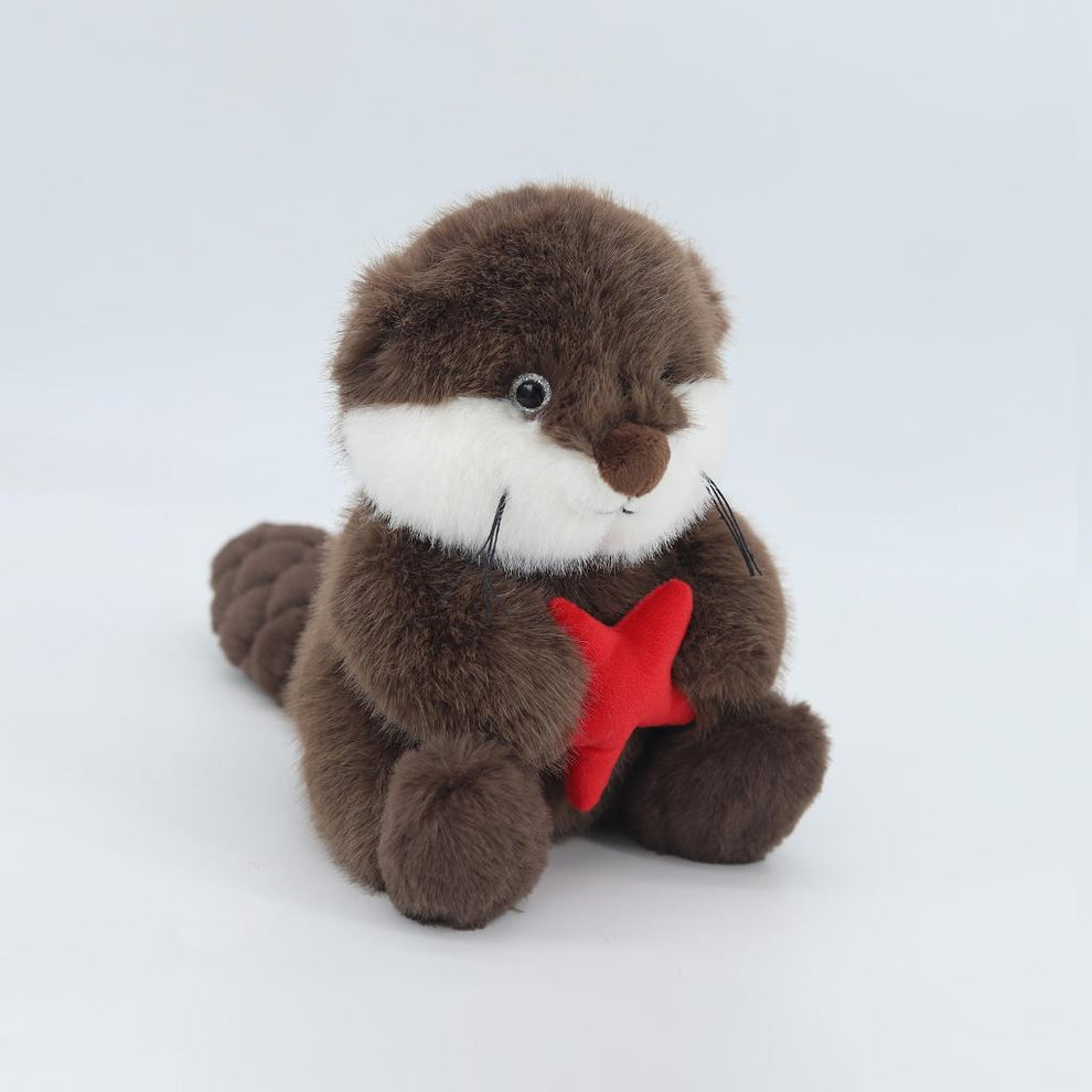 Plush toy otter holding a red star on a white background