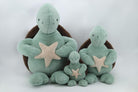 Set of three green plush turtles with star decorations on a white background