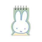 A Miffy-inspired spiral-bound notepad with a white bunny face outlined in light blue, a pale green background, and a small pale yellow area at the bottom, shown on a plain white background.