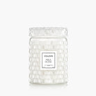 Clear glass candle jar with textured surface and Voluspa label on a white background