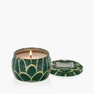 Green candle with gold patterns and a lit flame on a white background