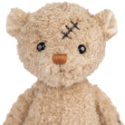 Stuffed teddy bear with a bandage on its head against a white background