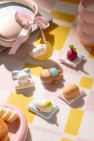 Cute sleeping animal figures in soft pastel colors by Smoko, arranged on checkered blanket with tiny pillows and accessories, lifestyle view