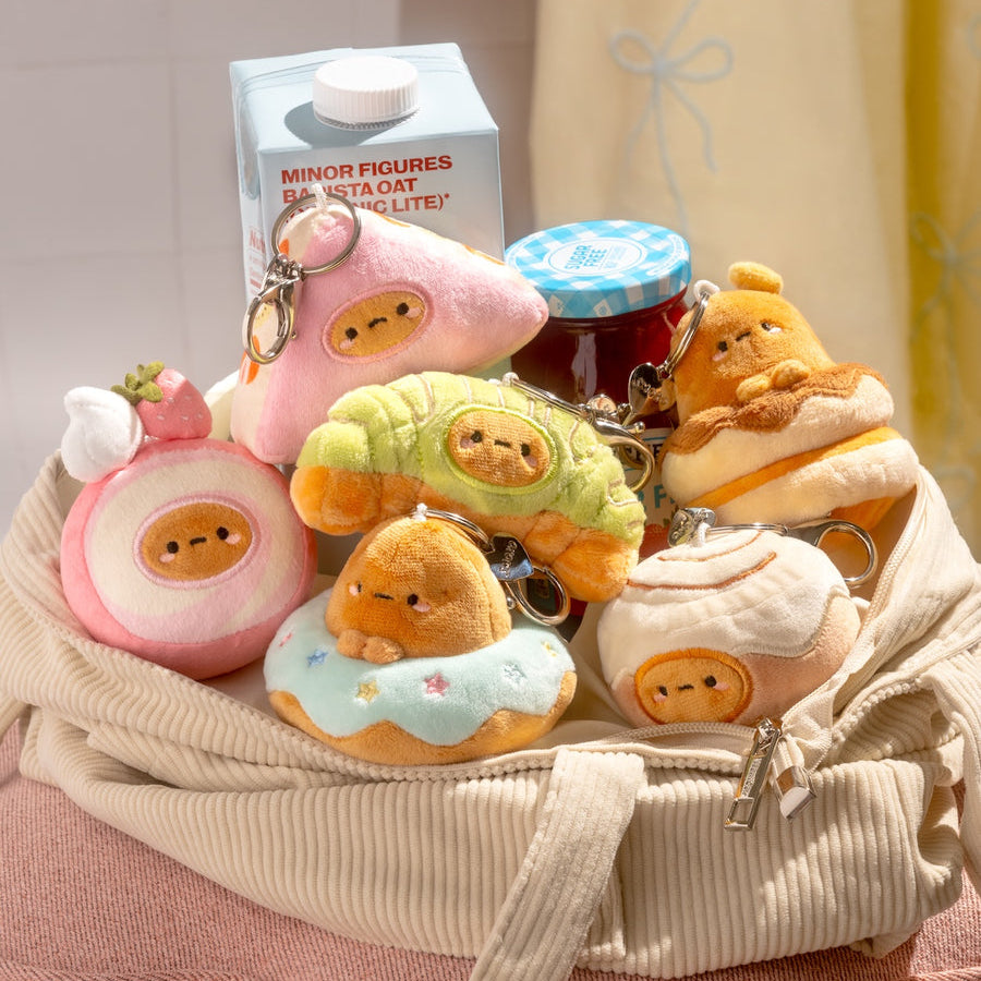 Collection of cute plush toys and keychains in a basket with a neutral background