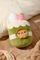 Plush toy resembling a character inside an avocado with a white cloud-like top, on a beige surface.
