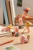Collection of small figurines on a desk with books and stationery items.