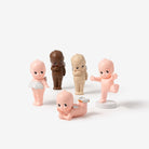 Set of five baby figurines with different skin tones on a white background