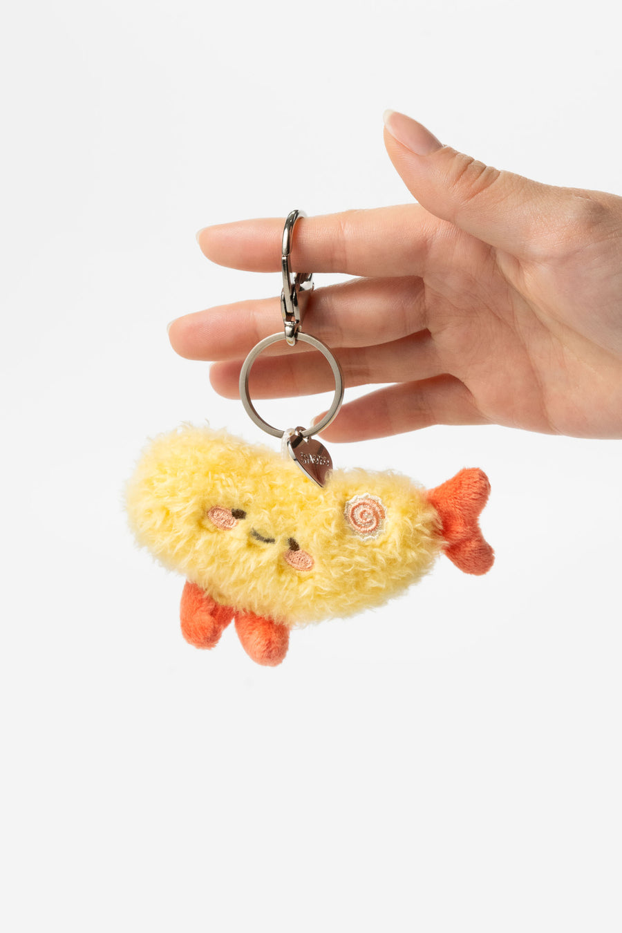 Hand holding a plush keychain shaped like a cloud with a face and orange feet against a white background