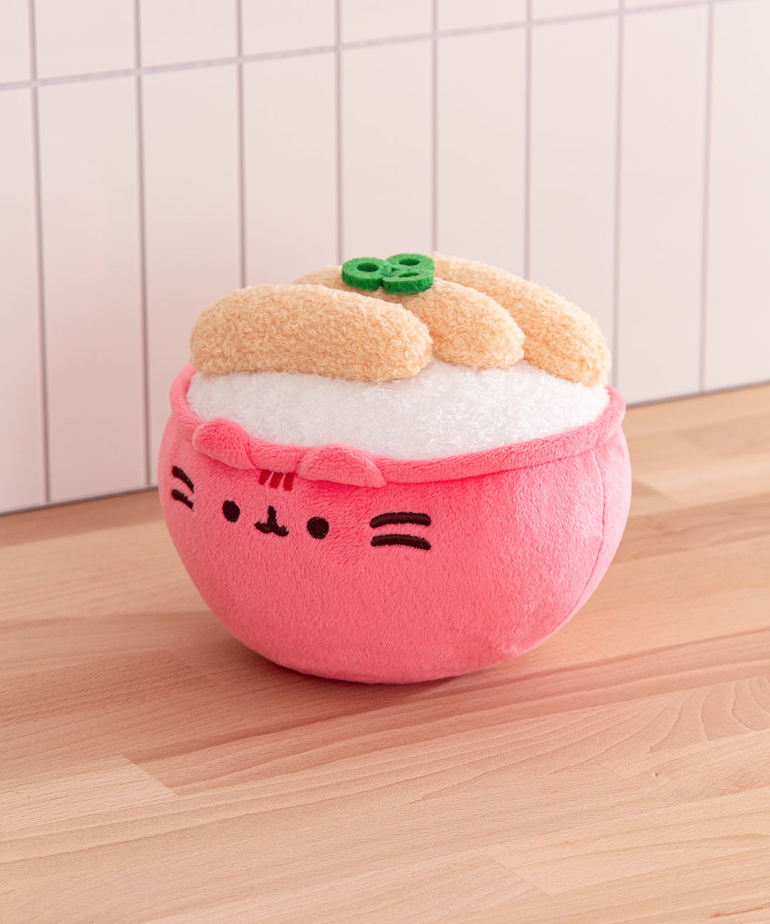 Plush toy shaped like a pink dumpling with a face on a wooden surface.