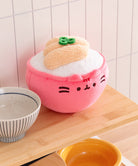 Plush toy shaped like a pink dumpling with a white filling on a wooden surface.