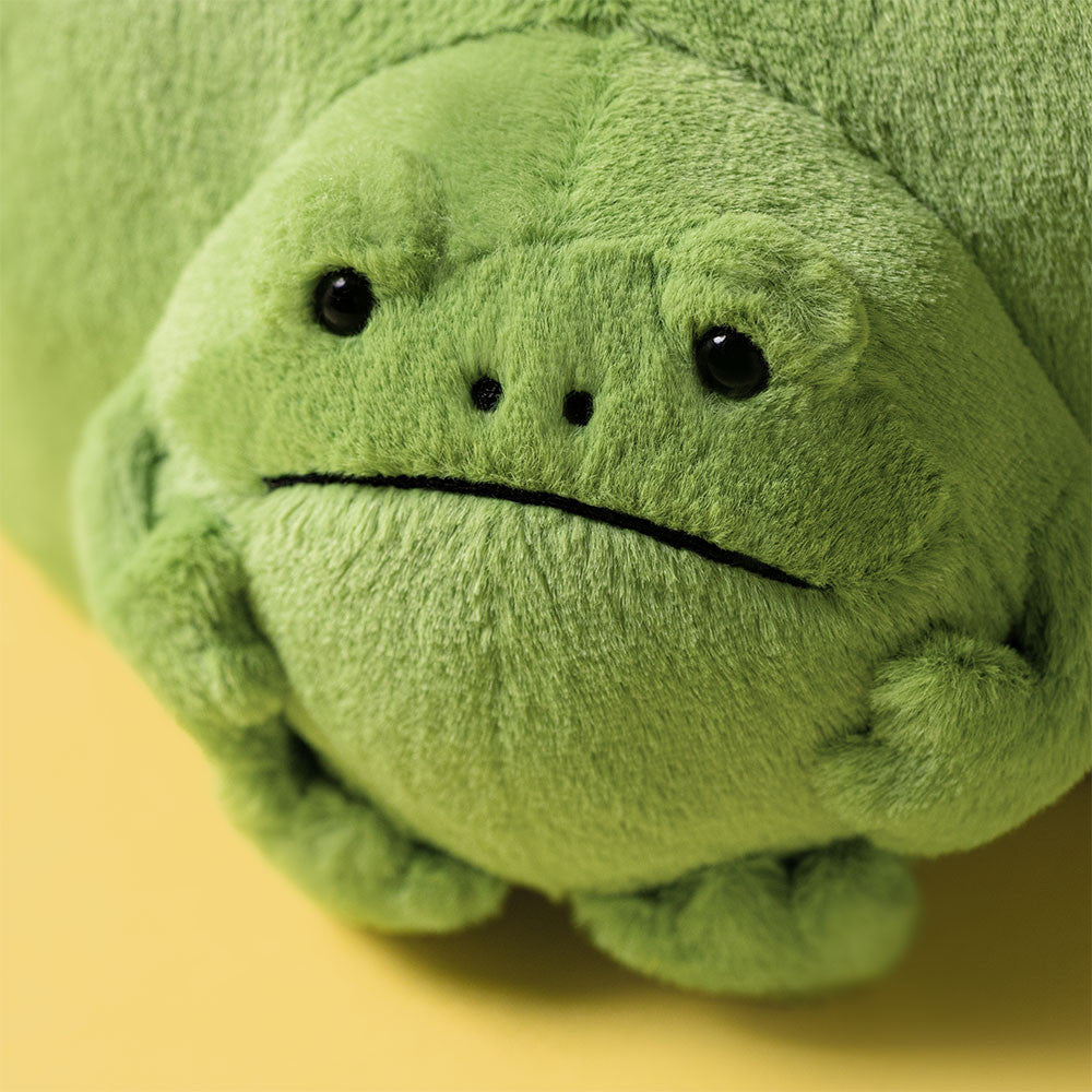 Green plush toy frog on a yellow background