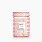 Pink textured candle jar with Voluspa label on a white background