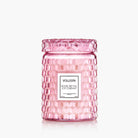 Pink Voluspa candle with textured glass and white label on a white background