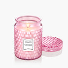 Pink Voluspa candle with a textured design on a white background