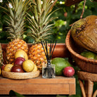 Fruit display with pineapples, apples, and a coconut on a wooden surface with a blurred green background.