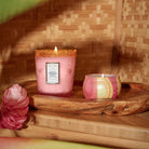 Two pink candles on a wooden tray with a woven background