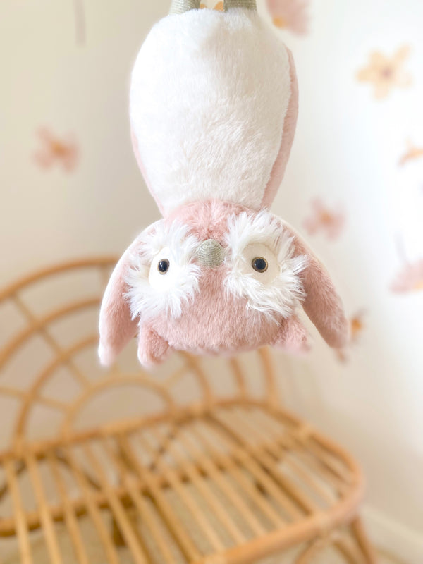 Upside-down, pink and white, plush owl toy.
