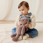 Baby holding a plush toy in a soft, neutral setting