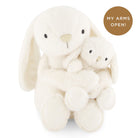 Two cream-colored plush bunnies embracing each other on a white background with a brown circle and text.