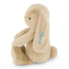 Beige plush bunny with blue embroidered name "Slovia" on ear, sitting side view, soft textured fur, 12-inch stuffed animal