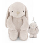A plush bunny toy in a light oatmeal beige color, shown next to a matching small plush keychain with a silver metal clip, on a solid white background.