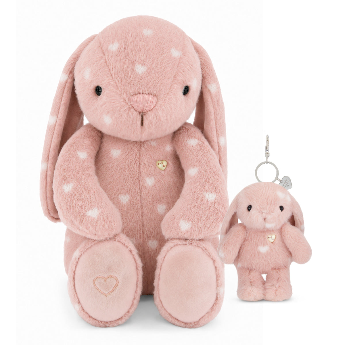 A pink plush bunny toy with white heart spots, shown alongside a smaller matching plush keychain with a silver clasp on a white background.