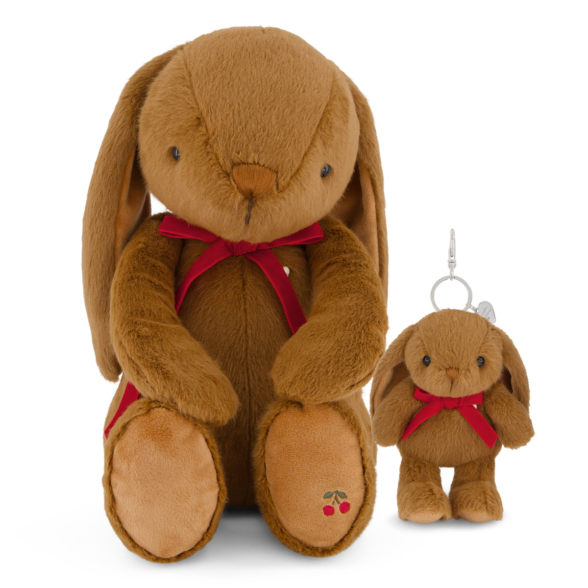 A large brown plush bunny toy with long floppy ears, a red ribbon bow, and embroidered cherries on its foot, shown next to a smaller matching plush keychain with a silver key ring on a white background.