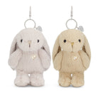 Two plush bunny keychains on a white background, one in pale pink-lilac and one in cream-beige, each with a small heart charm and silver key ring.