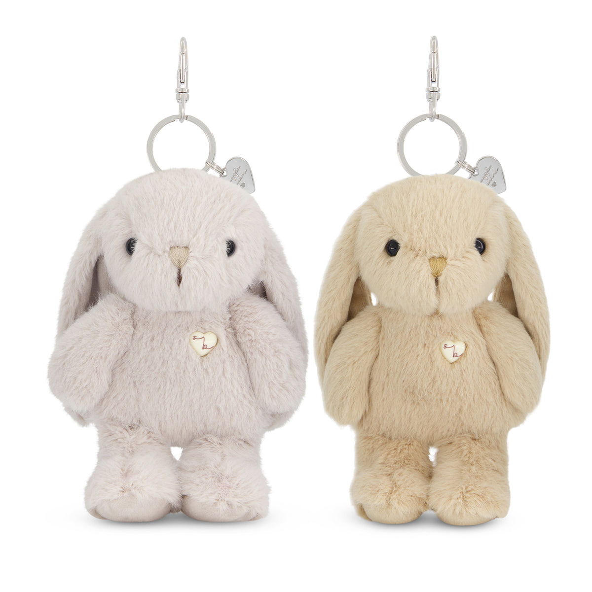 Two plush bunny keychains on a white background, one in pale pink-lilac and one in cream-beige, each with a small heart charm and silver key ring.
